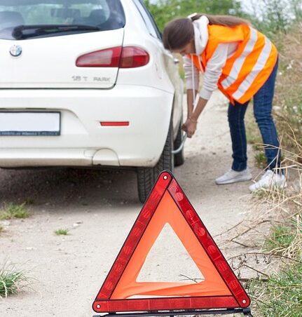 Carro con daños tras un accidente y triángulo de emergencia, símbolo de seguridad vial y respaldo en seguros vehiculares.